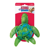 A green turtle-shaped dog toy with sea shell details, packaged on a red and white card.