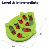 Green Nina Ottosson Buggin' Out cat puzzle with pegs, leaves, and treat compartments for interactive play.